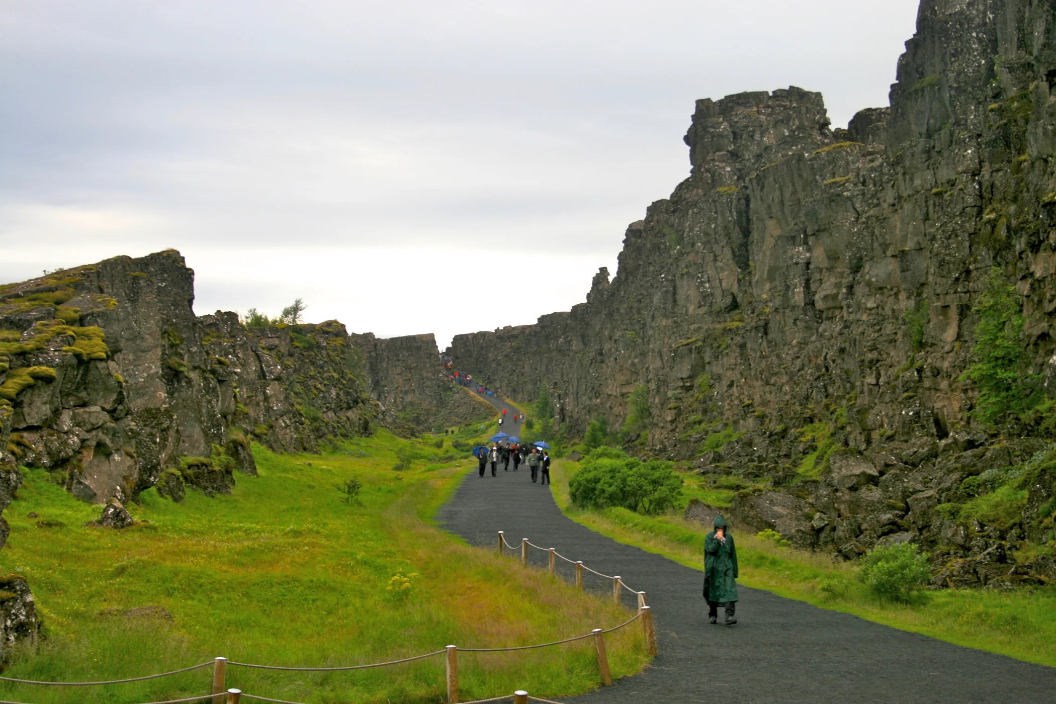 Visitors follow the path between Almannagjá’s rocky walls on a rainy day